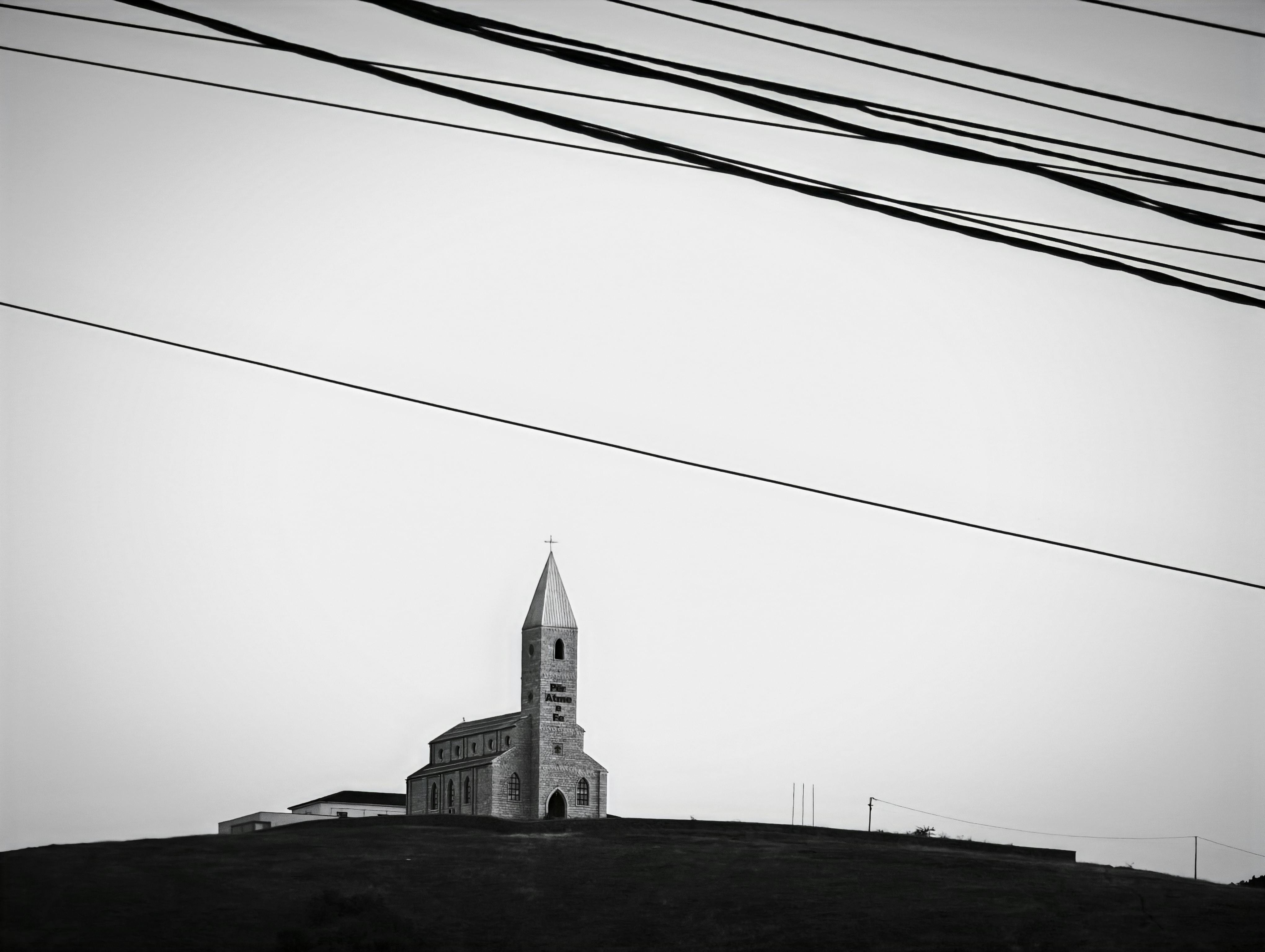 gratis Zwart-witfoto van een kerk op een heuvel in Orlat met elektriciteitsleidingen. Stockfoto