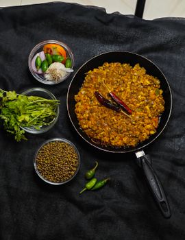 A vibrant flat-lay of Indian tadka dal with fresh herbs and spices.