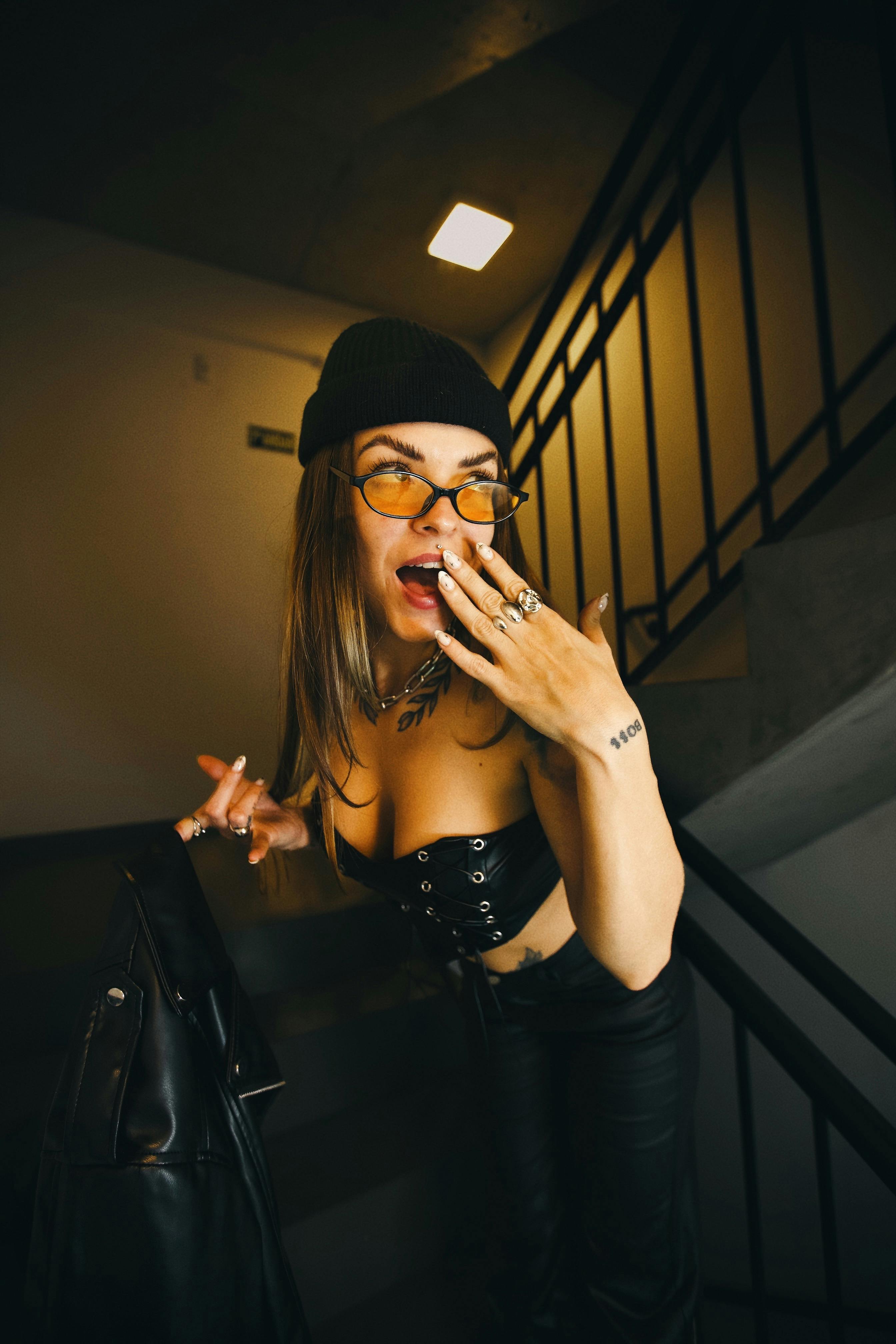 Miễn phí Người phụ nữ sành điệu đội mũ len và đeo kính tạo dáng ở cầu thang, trình diễn thời trang hiện đại. Ảnh lưu trữ