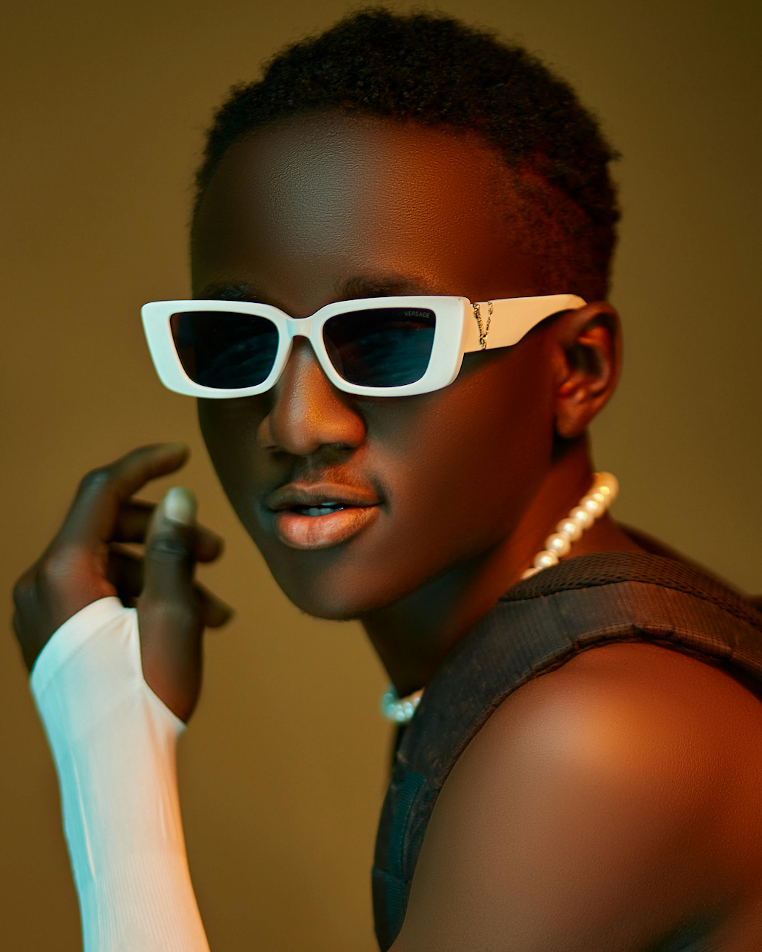 Free A fashion-forward portrait of a young African man wearing sunglasses and a pearl necklace. Stock Photo