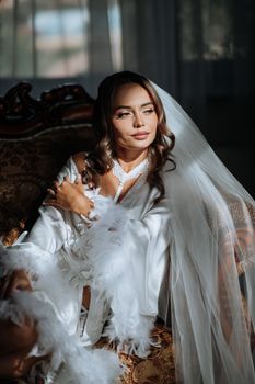 A glamorous bride in a silk robe and veil, exuding elegance.