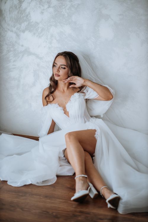 Free Charming bride in a white wedding dress sitting gracefully indoors. Stock Photo