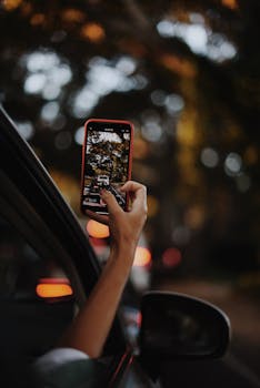 A car passenger captures scenic autumn moments with a smartphone in Los Angeles, California.