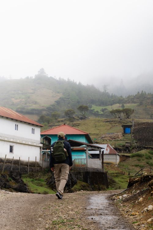 Free A lone traveler with a backpack ventures into a misty mountain village. Stock Photo