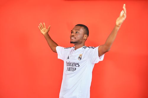 Free An enthusiastic football fan celebrating with arms raised in a jersey against a red background. Stock Photo