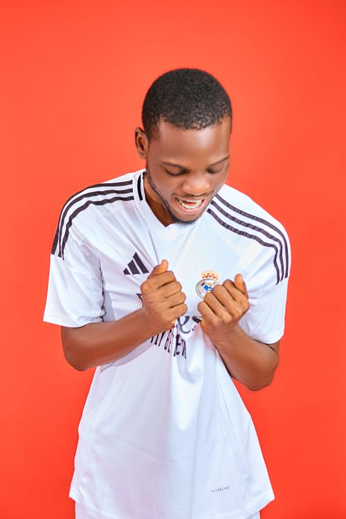 Free Happy young man in a soccer jersey celebrating against a vibrant red background. Stock Photo