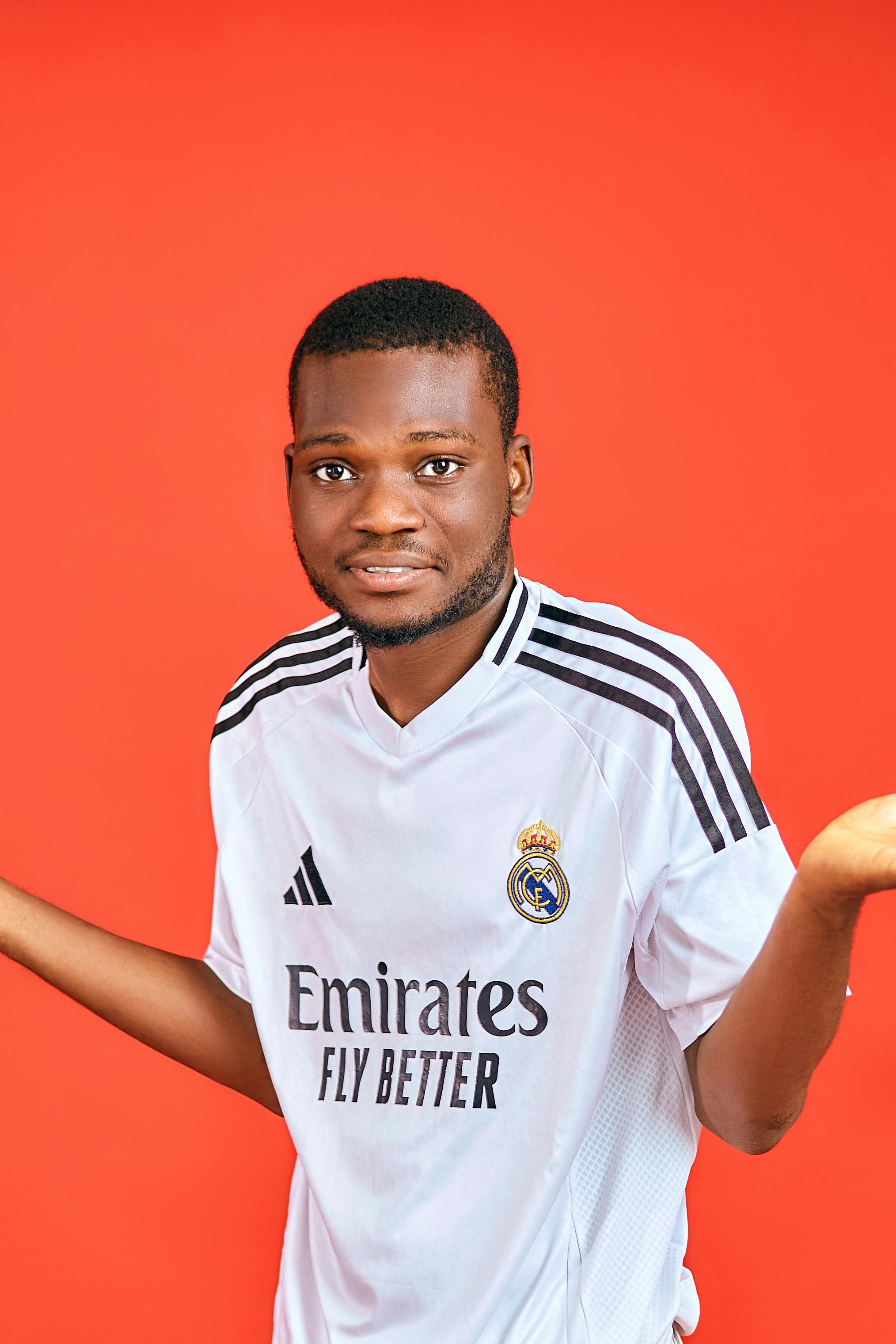 Smiling young man in a sports jersey against a vibrant red background.