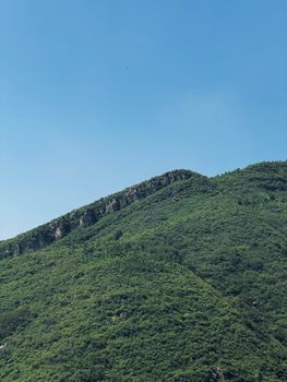 A serene view of a green mountain under a bright blue sky, perfect for nature photography.