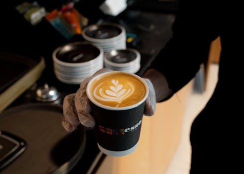 A barista serves a cup of coffee with stunning latte art in a cozy cafe setting.