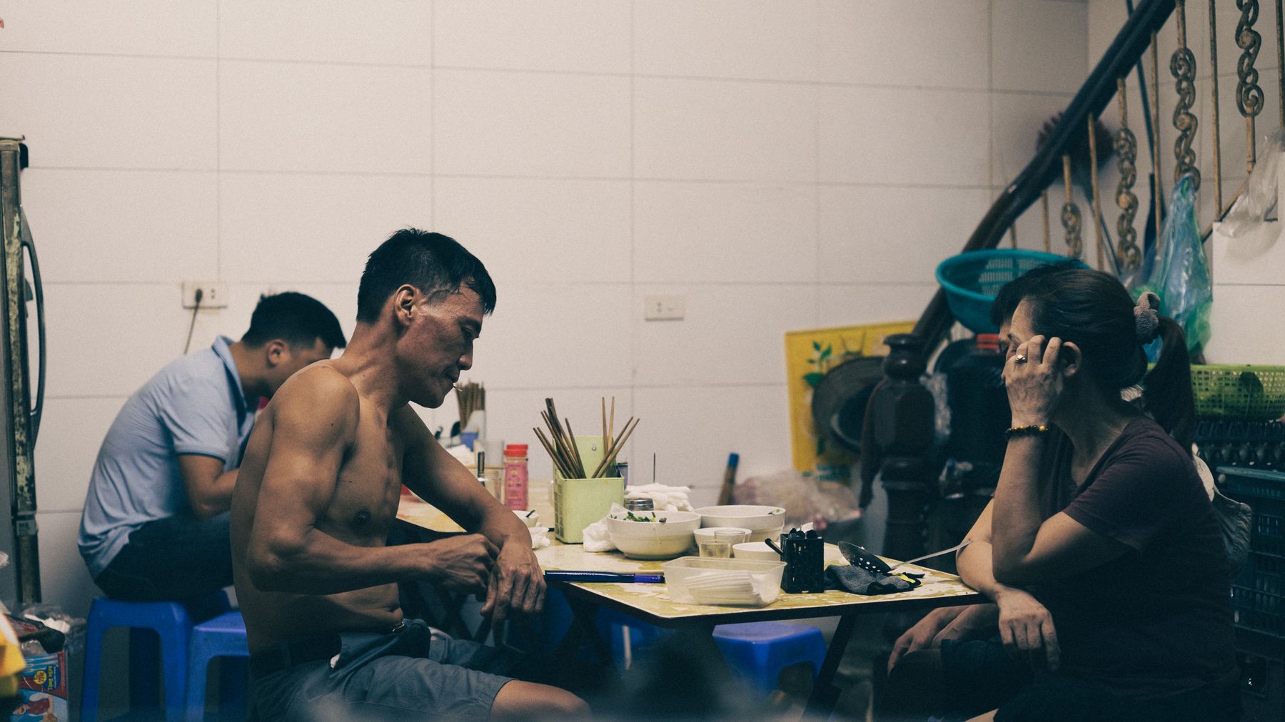 Intimate scene of friends dining indoors at a local spot in Hanoi, Vietnam, showcasing urban life.