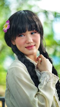Charming portrait of a woman with braided hair and a flower in her hair, set outdoors.