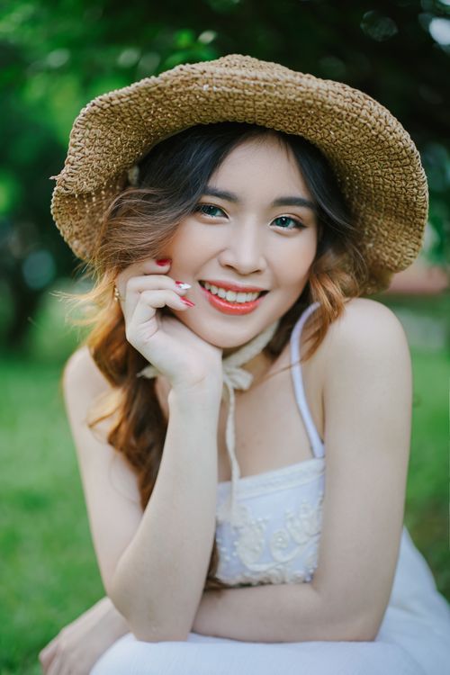 Free Cheerful woman wearing a straw hat, smiling in a sunny garden. Stock Photo