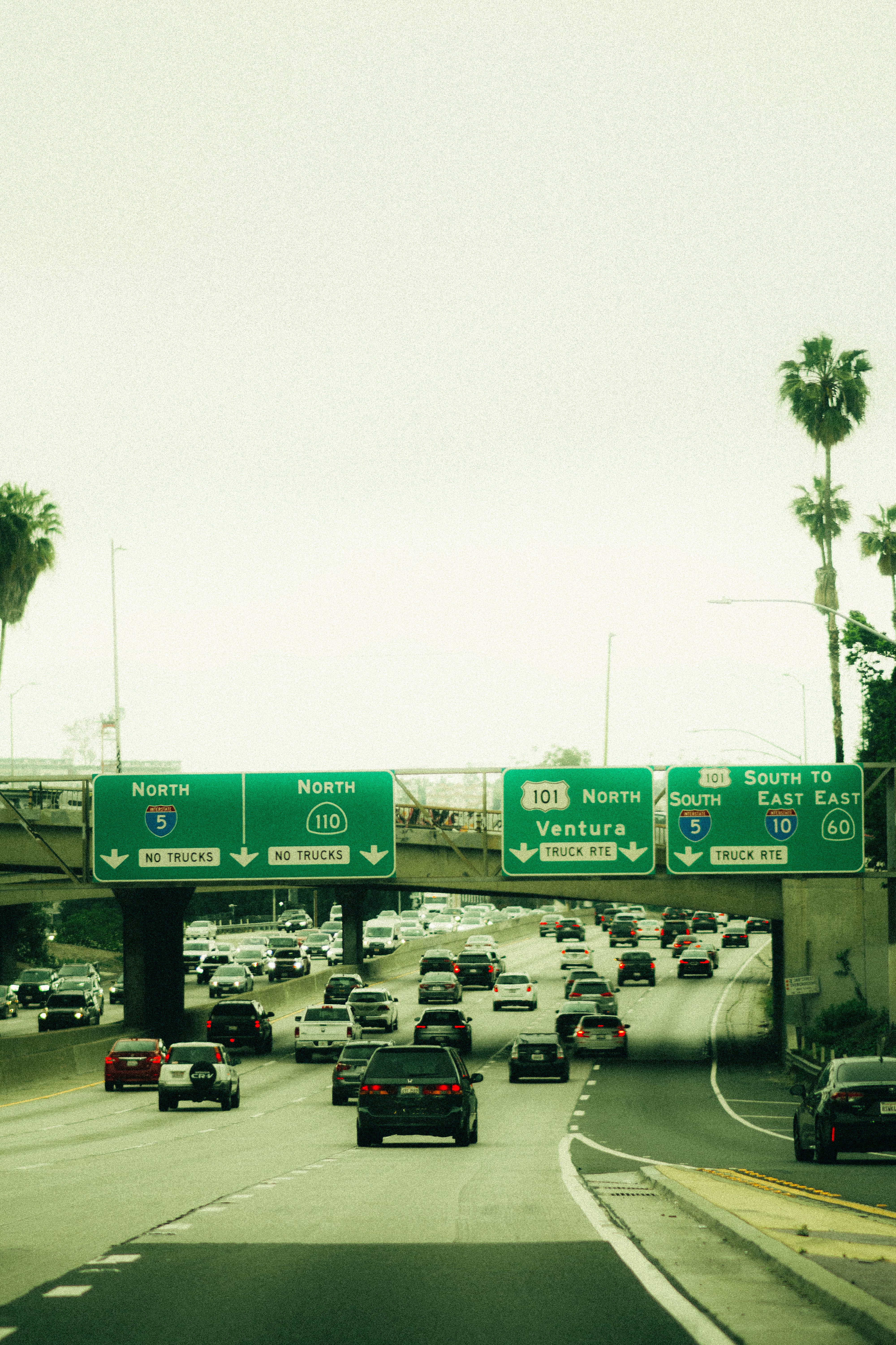 Traffic moving on a wide Southern California freeway under a clear blue sky.