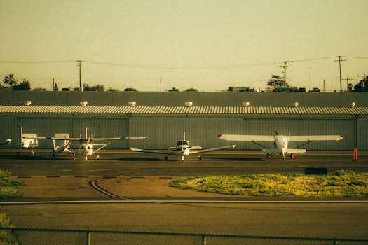 Four private airplanes parked on a sunlit airfield runway, captured at sunset.