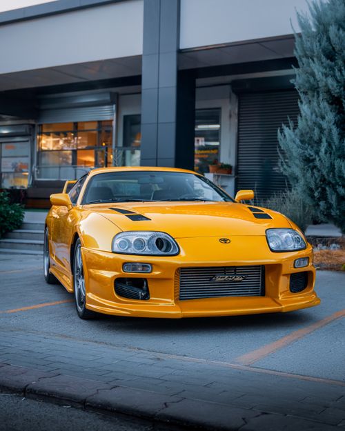 Free A striking yellow Toyota Supra parked outside a modern building in Ankara, Türkiye. Stock Photo