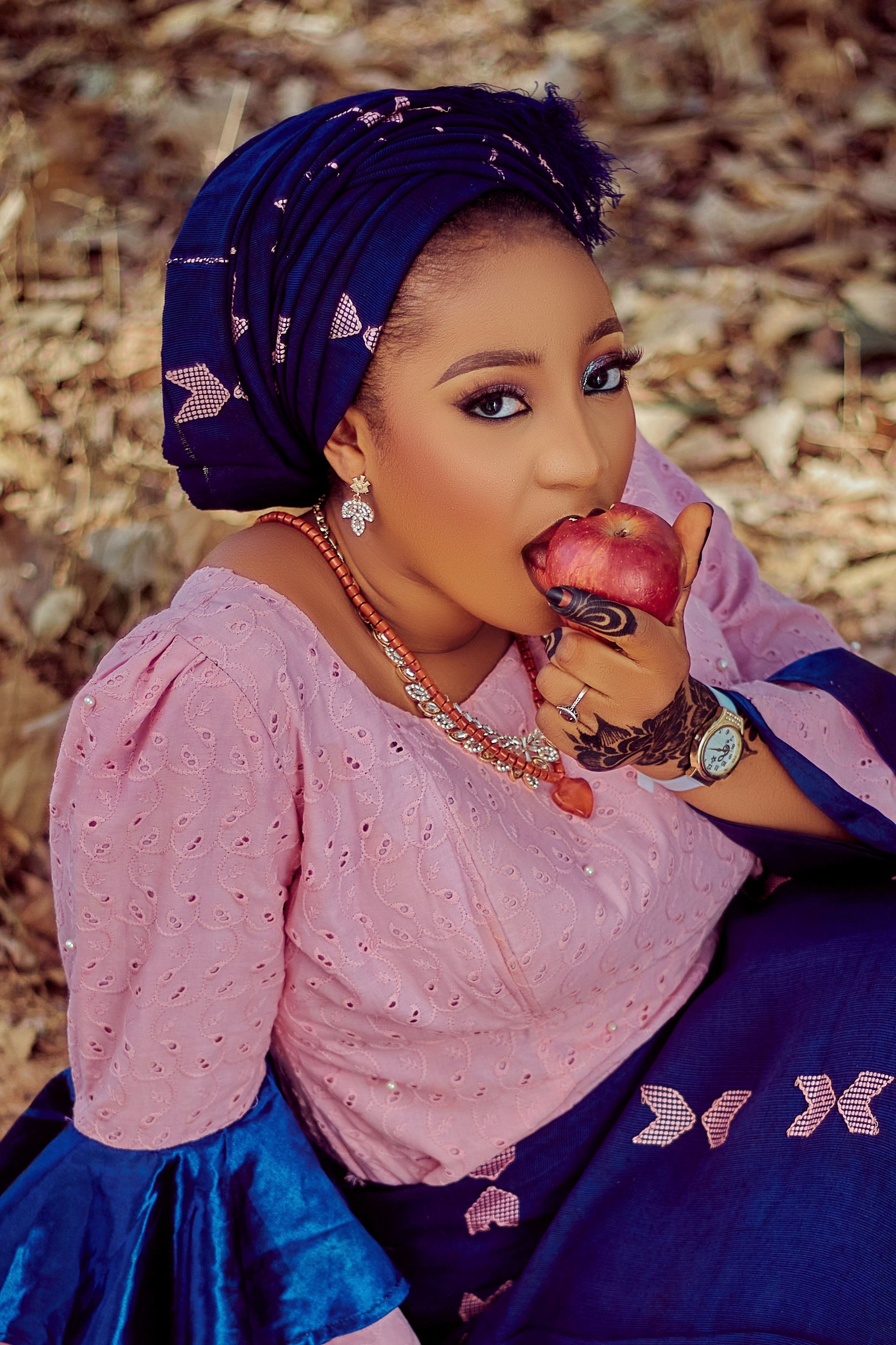 Stunning portrait of a woman wearing traditional clothes enjoying an apple outdoors.