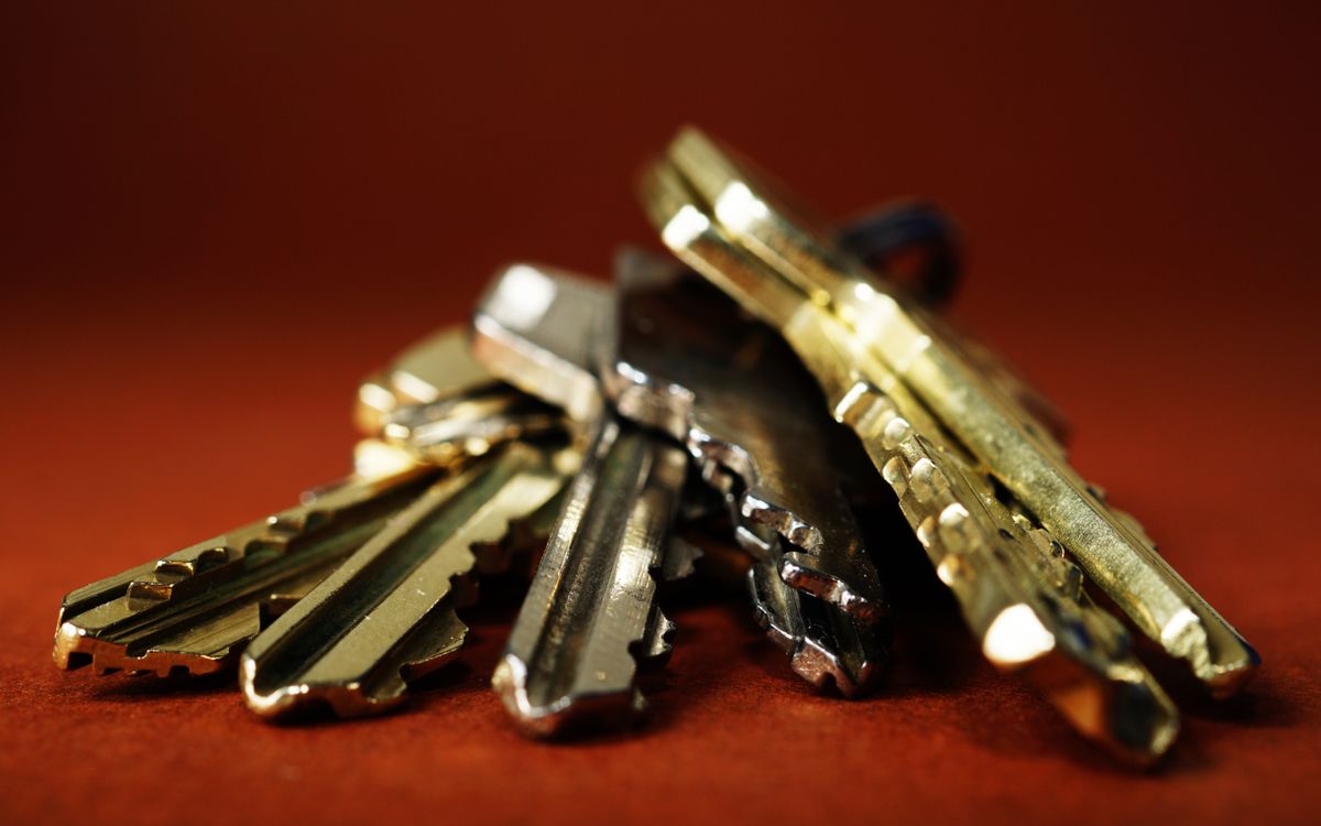 Brass-colored keys resting on a flat surface, warm metallic tones echoing the brand brass accent