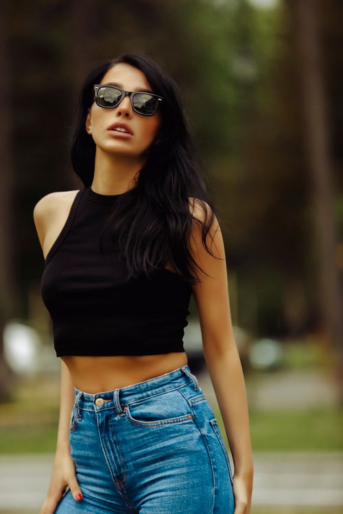 Free Fashionable woman posing outdoors in sunglasses and casual outfit, exuding confidence and modern style. Stock Photo