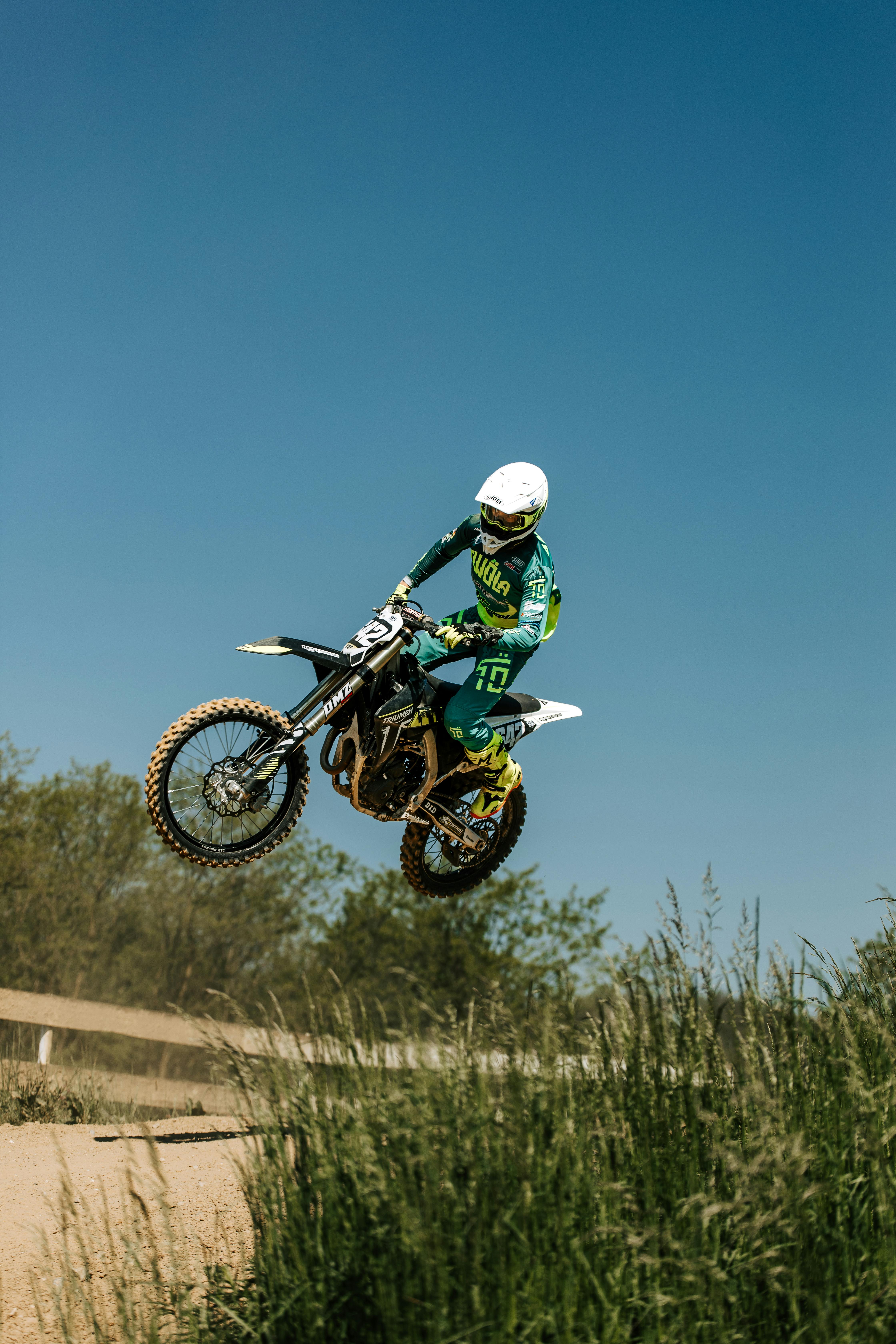 Adrenaline-pumping motocross jump captured mid-air against a clear blue sky.
