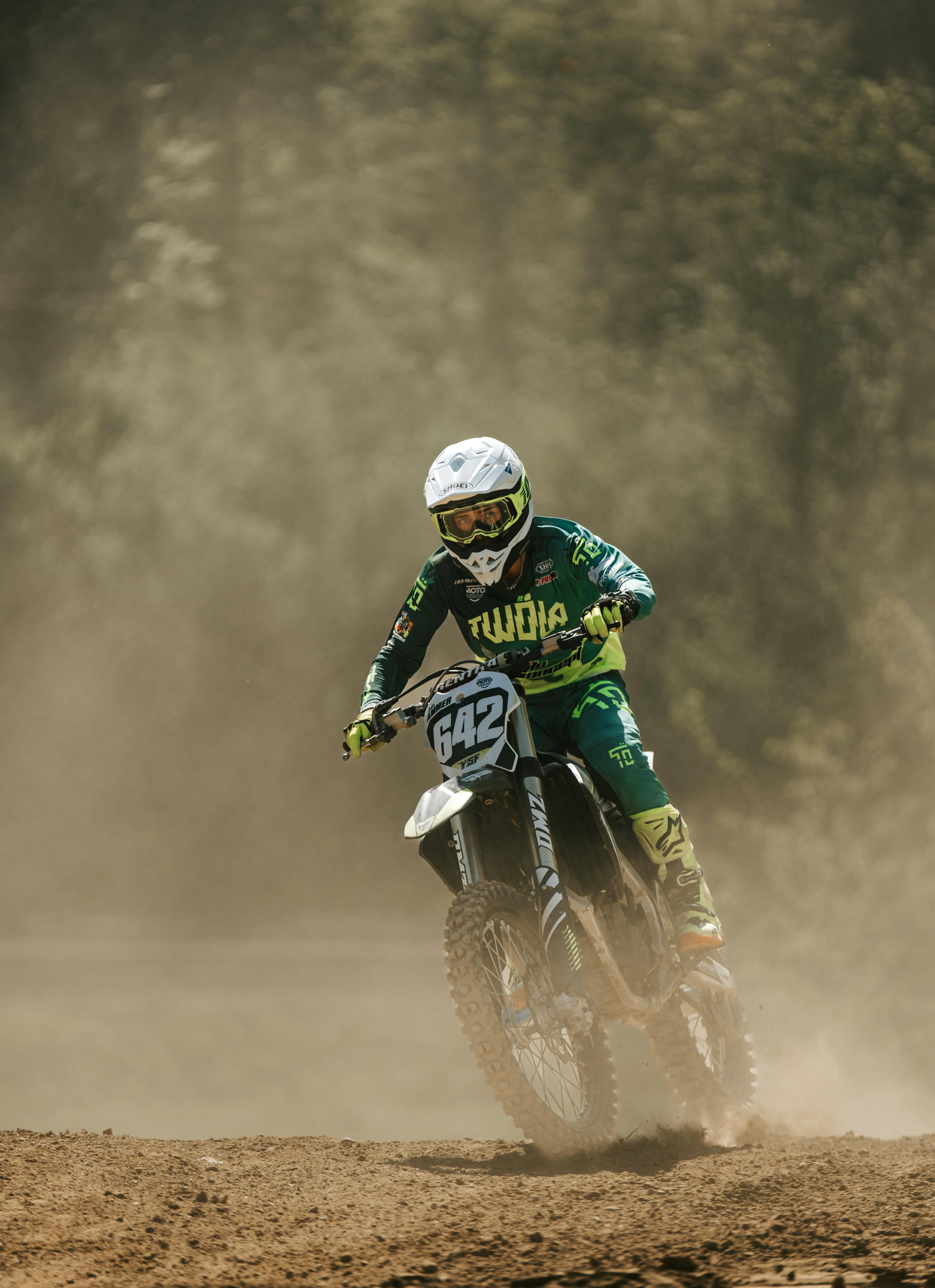 Motocross rider speeds down a dusty track in full gear, showcasing agility and control.