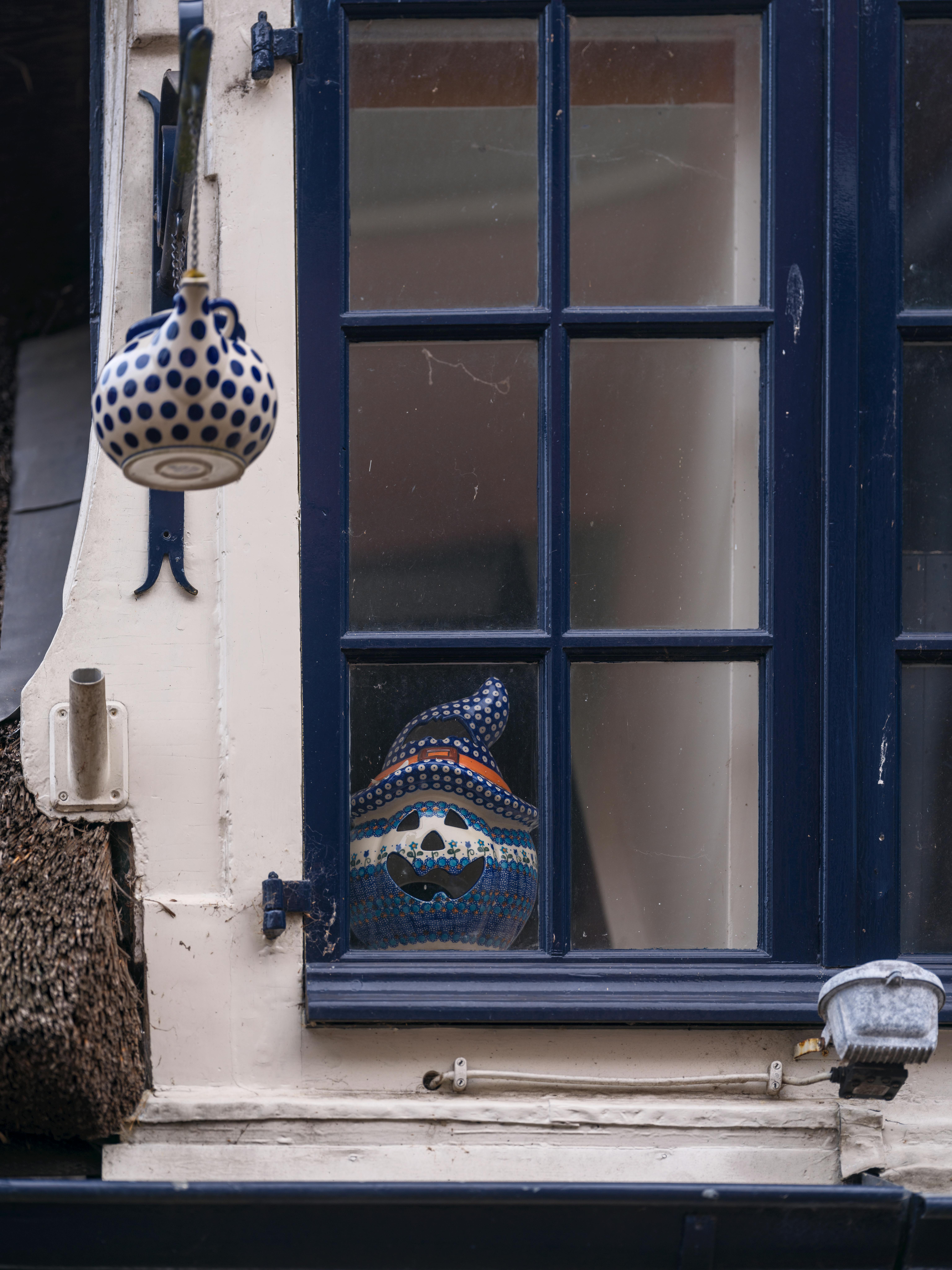 Artistic pottery teapot and pumpkin decor in a charming Dutch window setting.