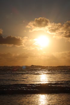 Sunset over the ocean at Lacanau, France. Warm hues and clouds create a stunning seaside view.