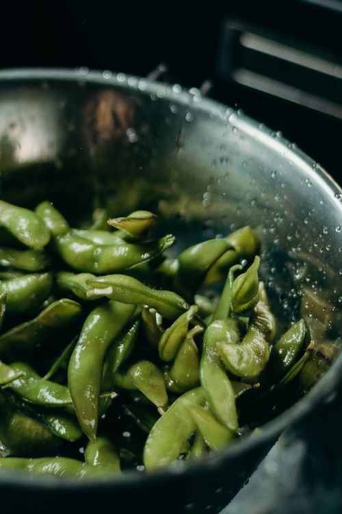 Free Close-up of fresh edamame beans being washed in a colander, highlighting their vibrant green color and freshness. Stock Photo