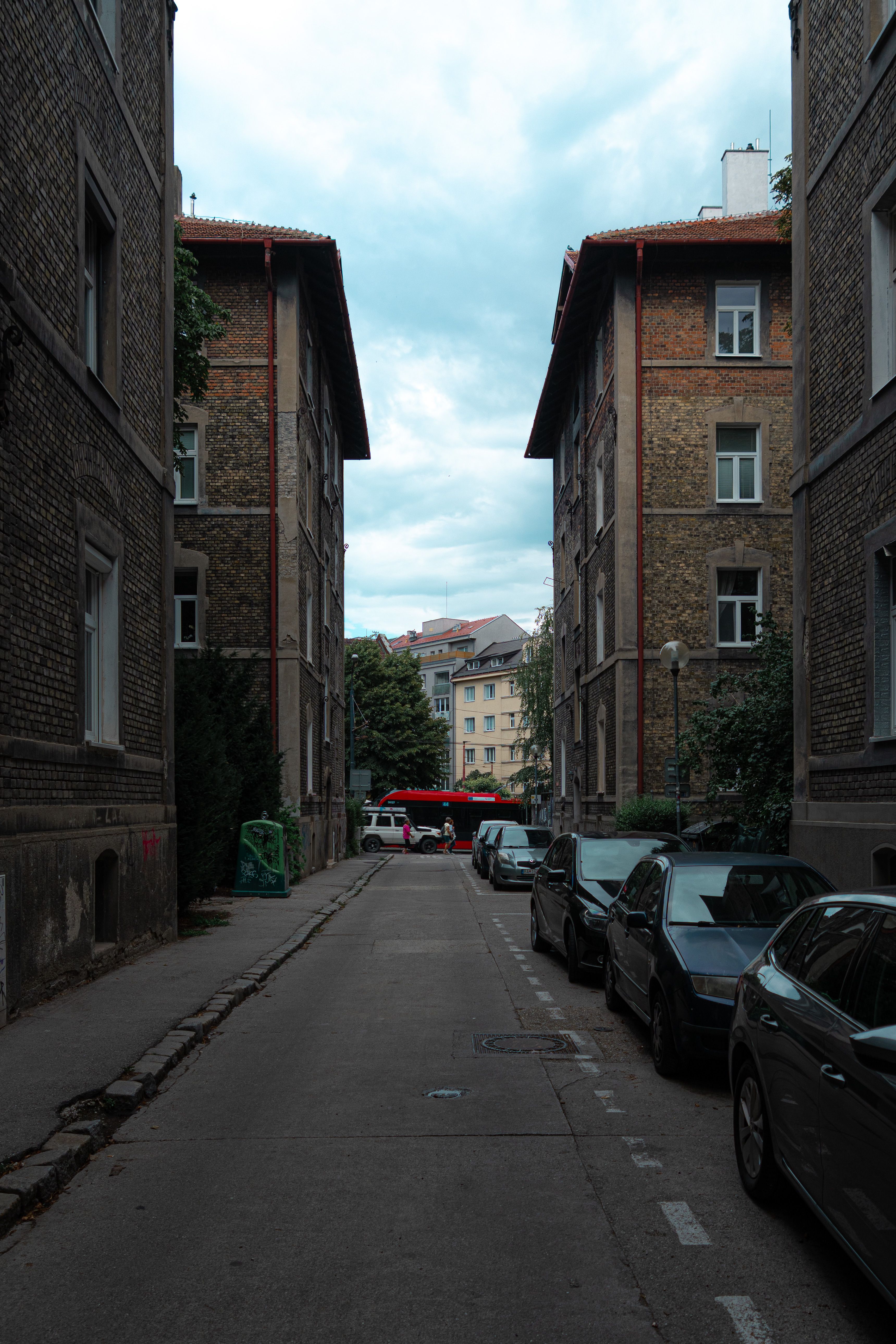 Narrow Urban Street with Parked Cars and Old Buildings · Free Stock Photo