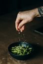 一只手将盐撒在新鲜的毛豆上，捕捉到准备美味饭菜的瞬间