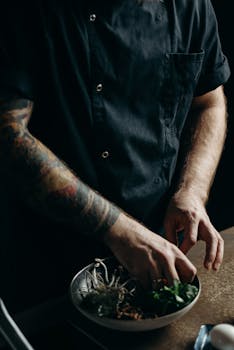 在喜怒无常的厨房环境中，纹身厨师将食材放入碗中，打造一道美食