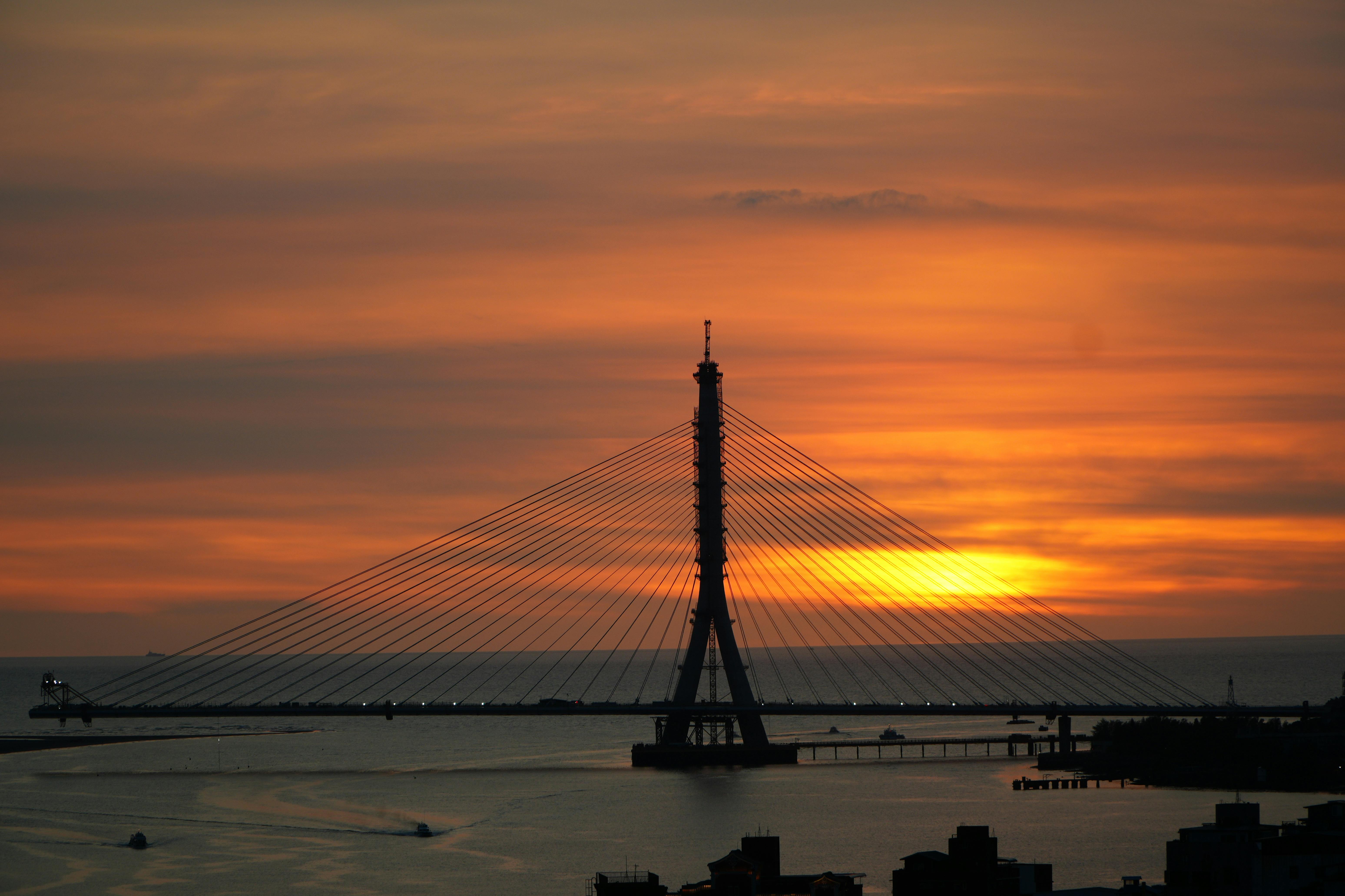 A beautiful sunset behind Tamsui River Bridge in New Taipei City, Taiwan, with warm orange hues