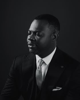 Black and white portrait of a confident businessman with eyes closed, wearing a suit and tie.