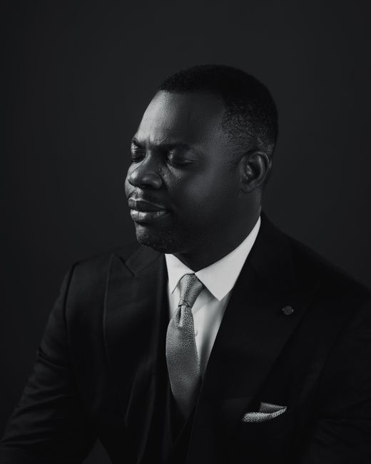 Black and white portrait of a confident businessman with eyes closed, wearing a suit and tie.