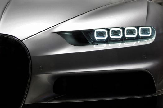Close-up of luxury sports car headlight with sleek design and modern LED lights at night.