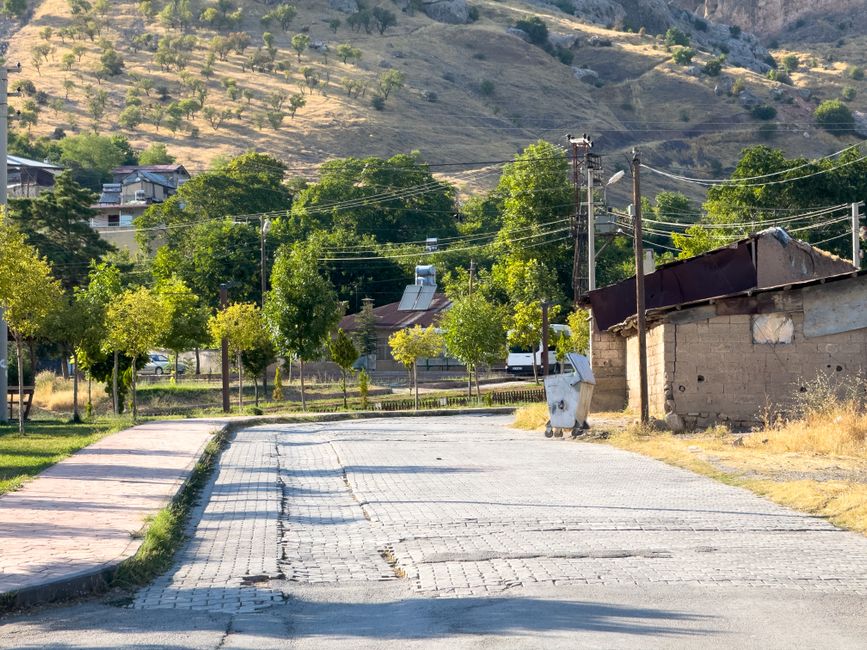 A quaint street in Elazığ, Türkiye, with rustic charm and a backdrop of lush hills.