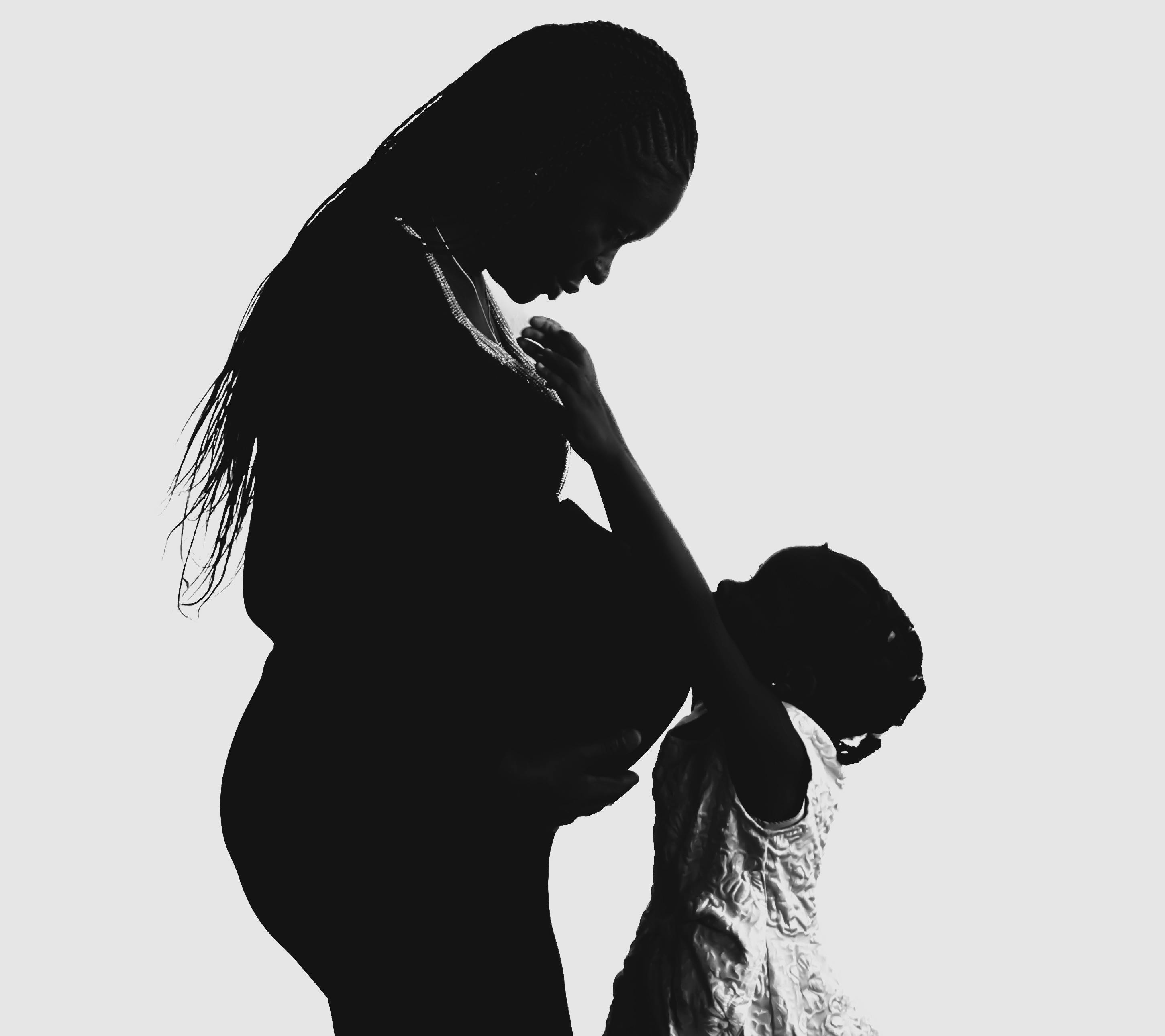 Silhouette of a pregnant woman with a child, highlighting love and maternal bond.