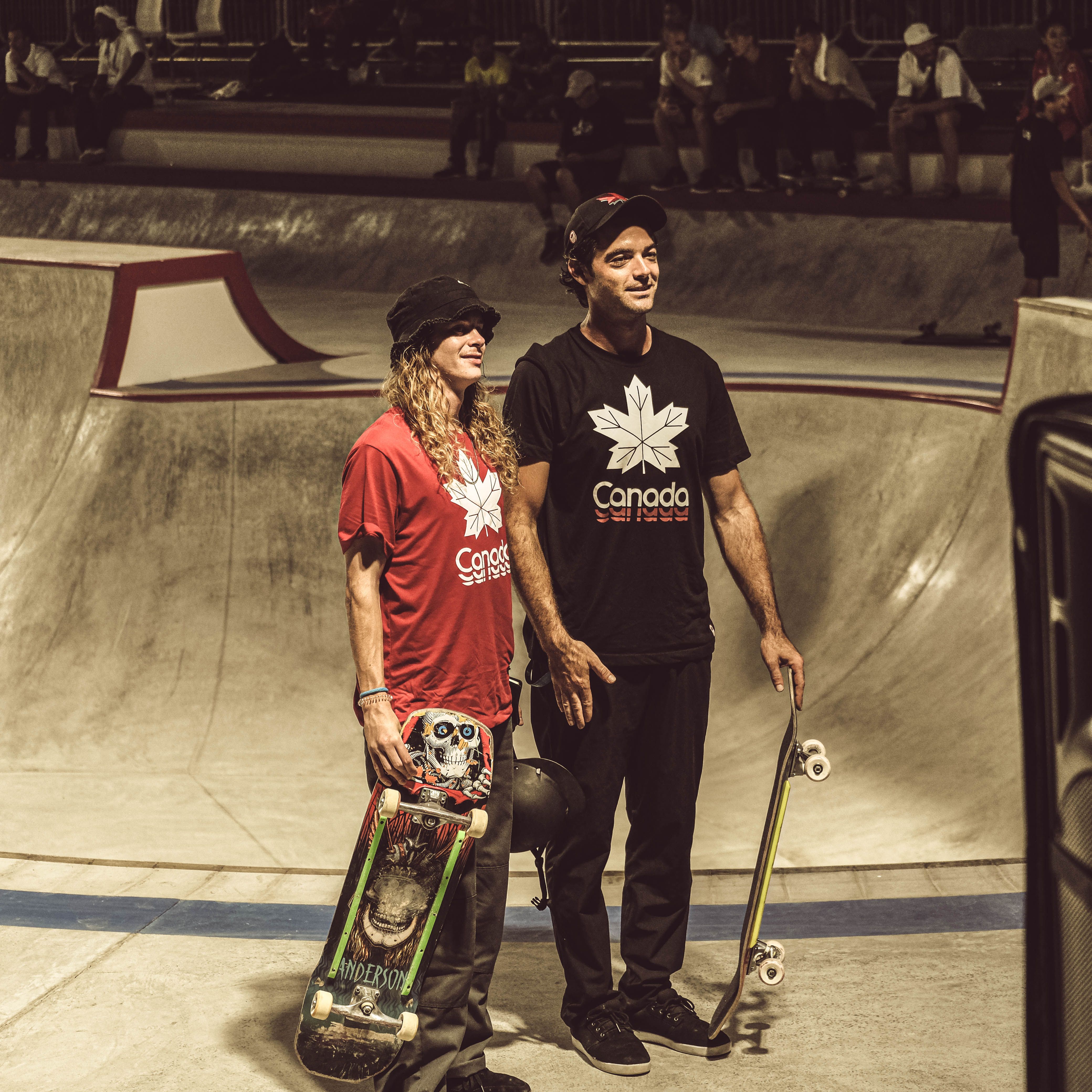 Two skateboarders in Canadian shirts pose at a skatepark, showcasing national pride.