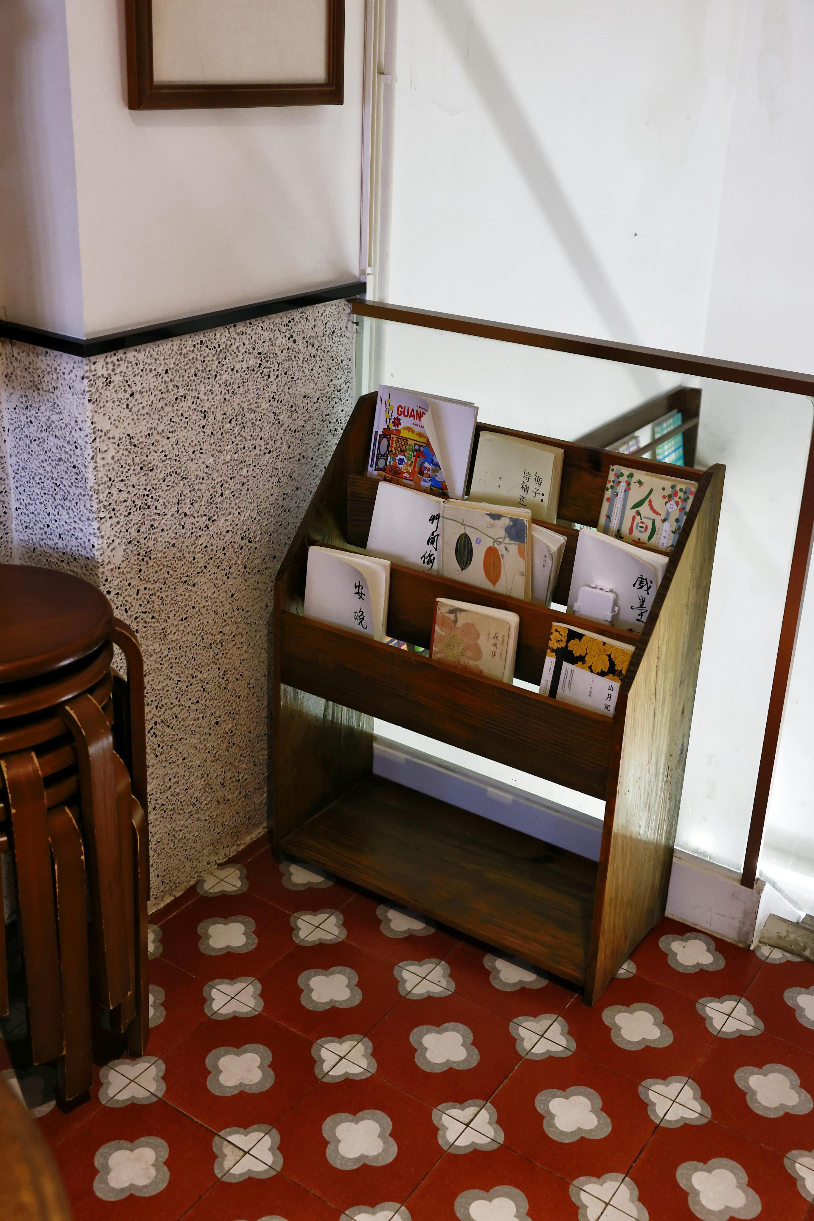 Free A cozy coffee shop corner with a wooden book display and vintage tiles. Stock Photo