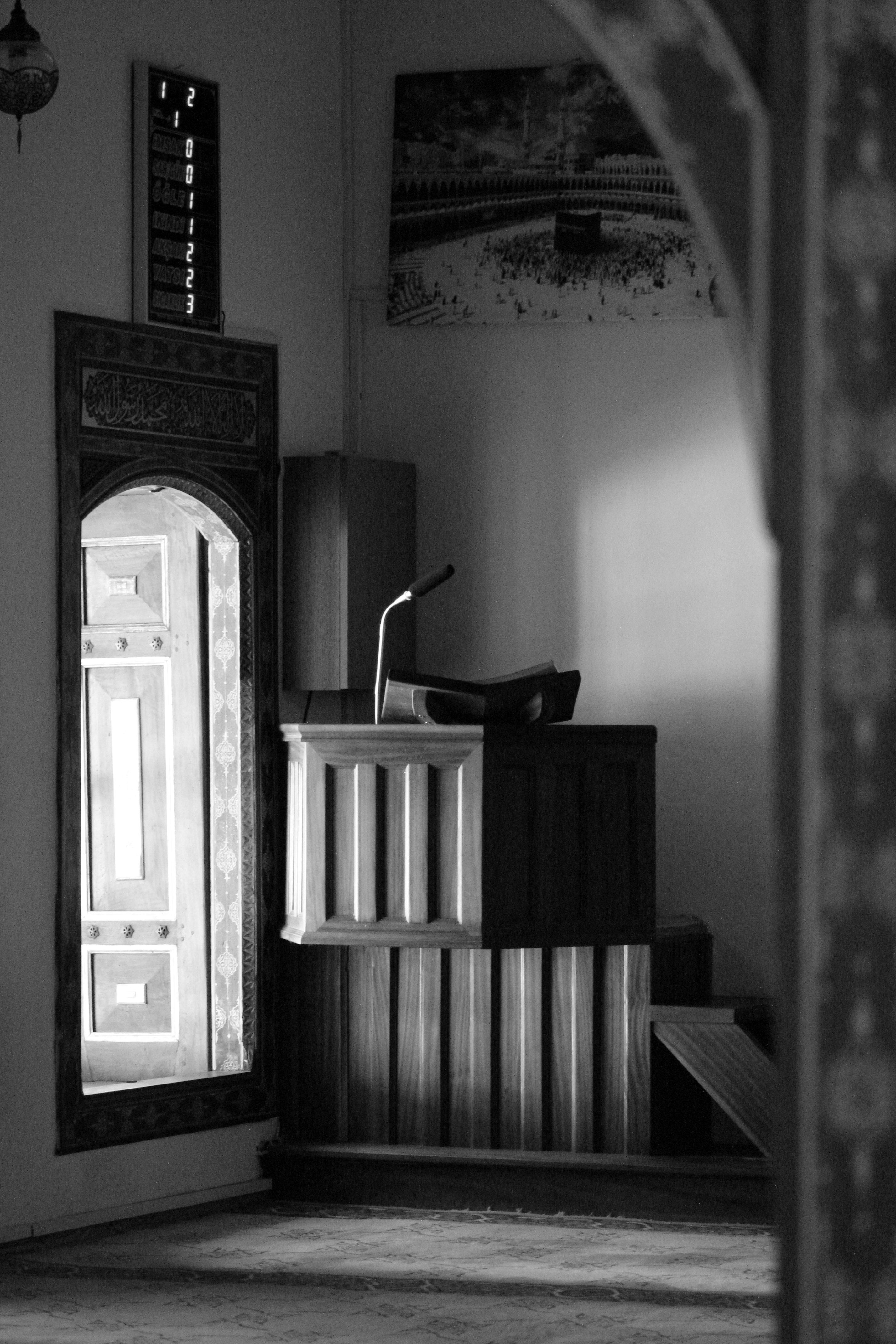 Black and white interior of a mosque with a pulpit and wooden details.