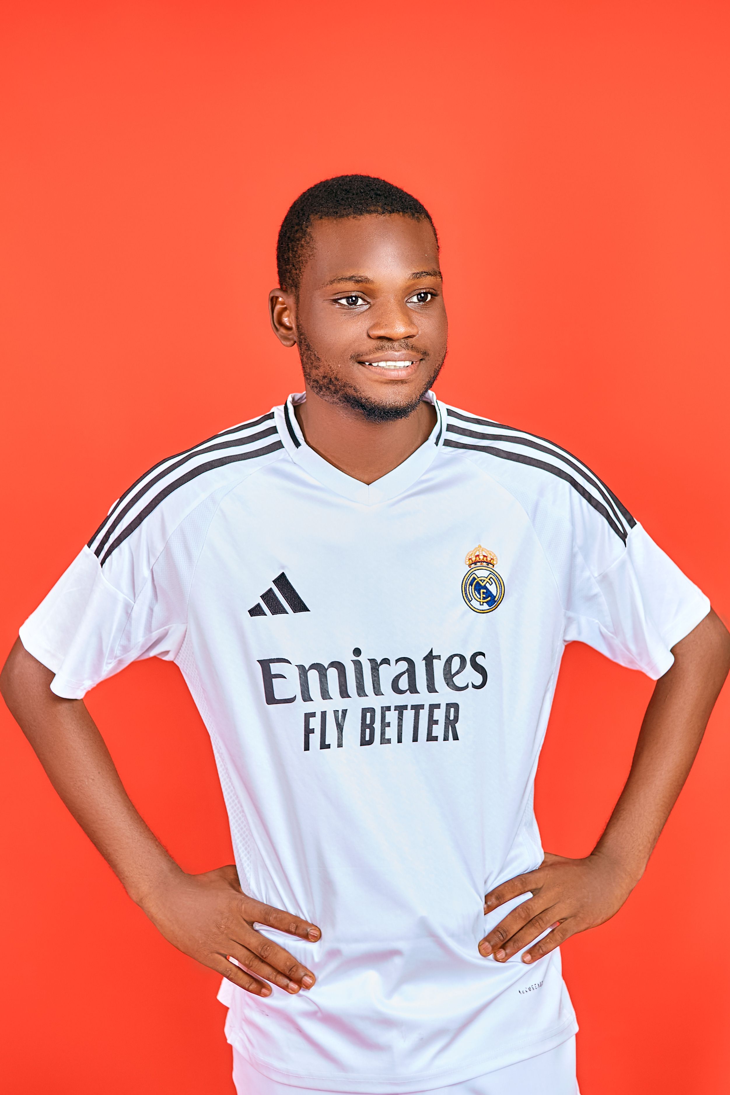 Young man in sports jersey posing confidently against a vibrant red backdrop.