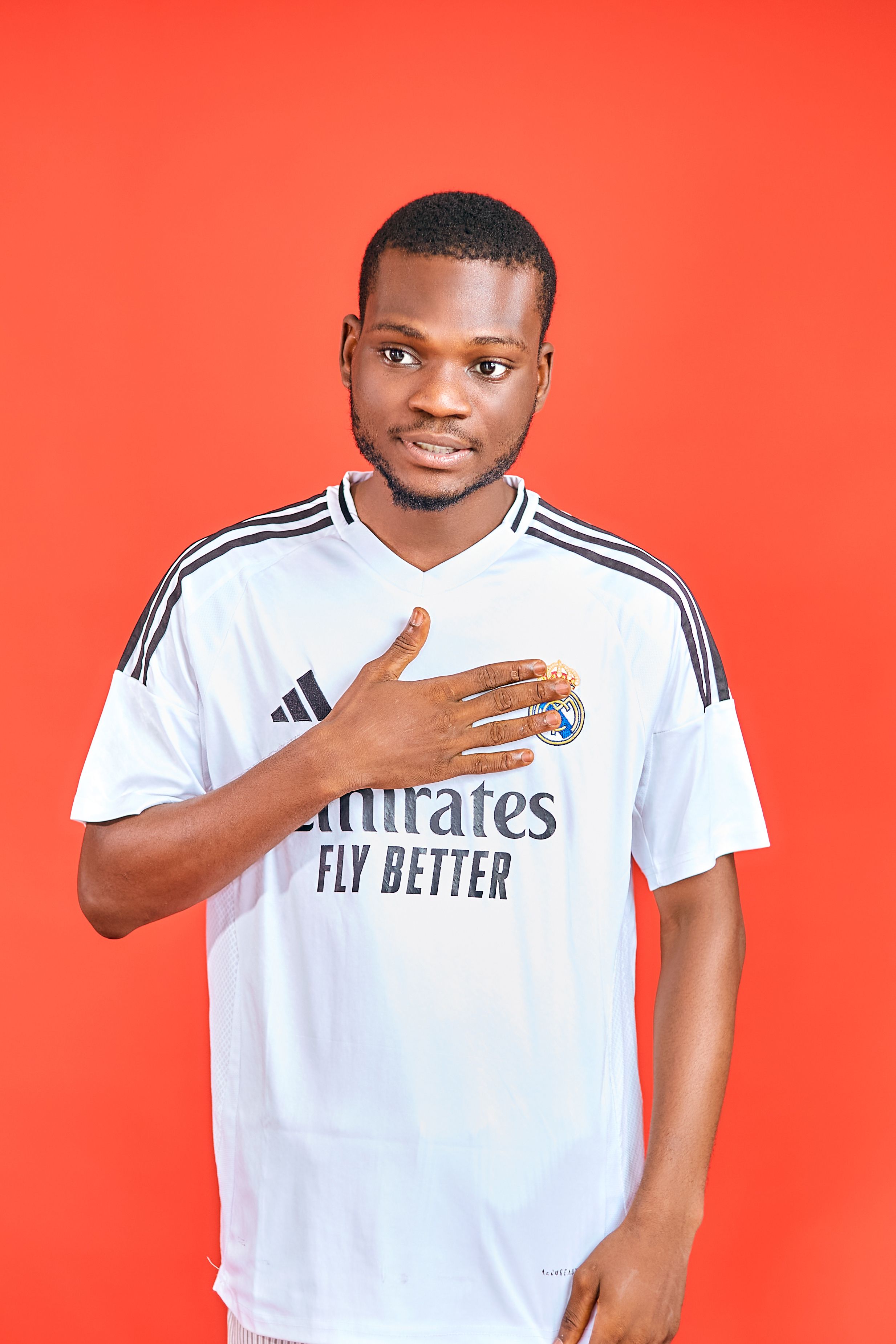 Portrait of a young man in a soccer jersey with a vivid red background.