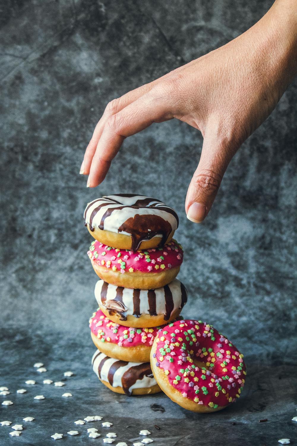 stack of donuts. hand reaching for the one on top
