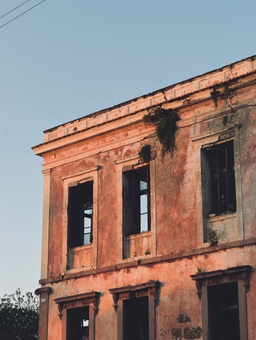 Free Old, weathered building captures the warmth of sunset showing decay and beauty. Stock Photo
