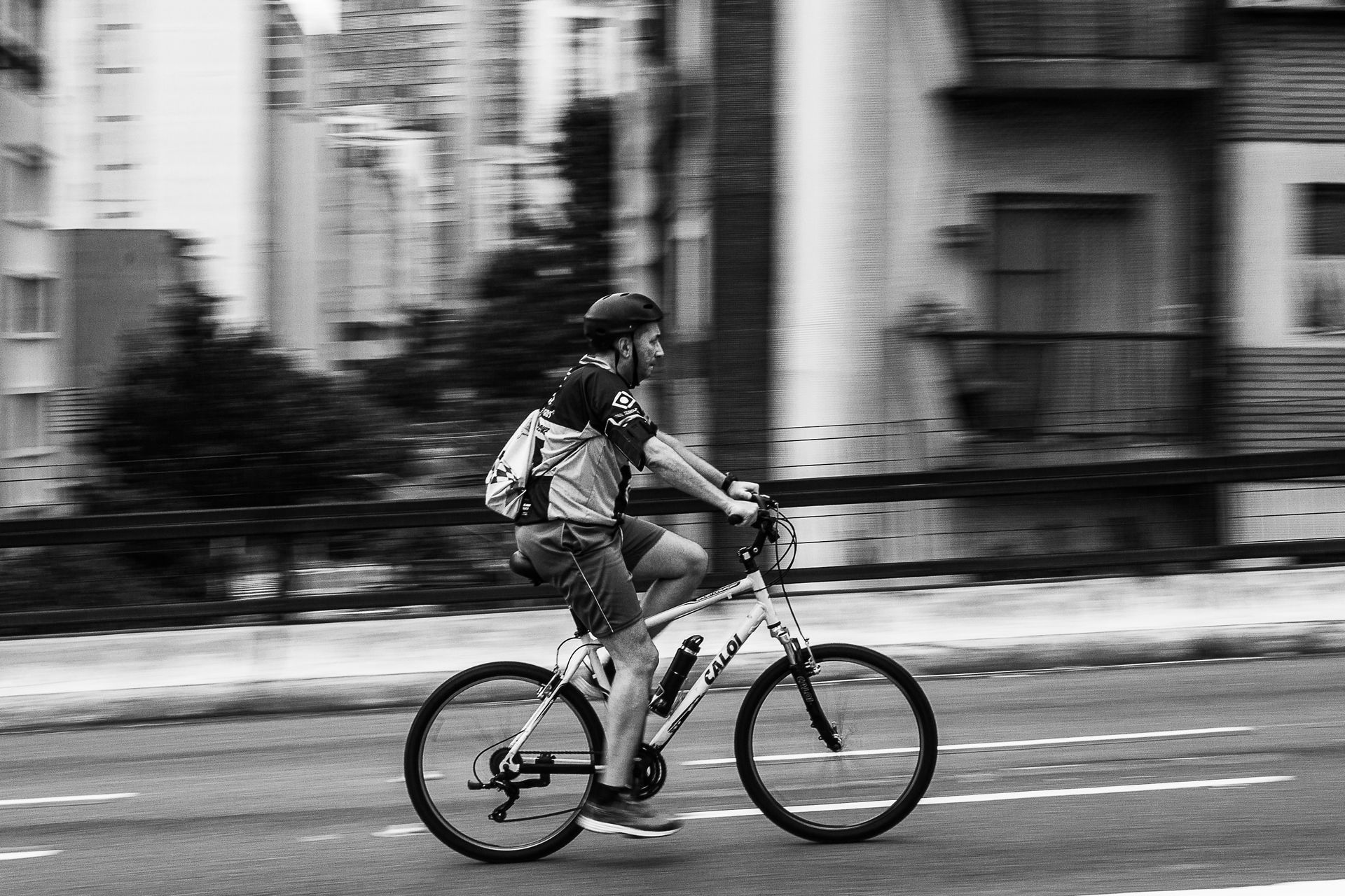 Dynamic black and white shot of a cyclist in mid-motion on a city street, emphasizing speed and urban life.