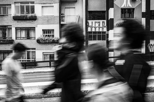 Blurred motion of people walking in front of urban buildings, creating a dynamic city scene.