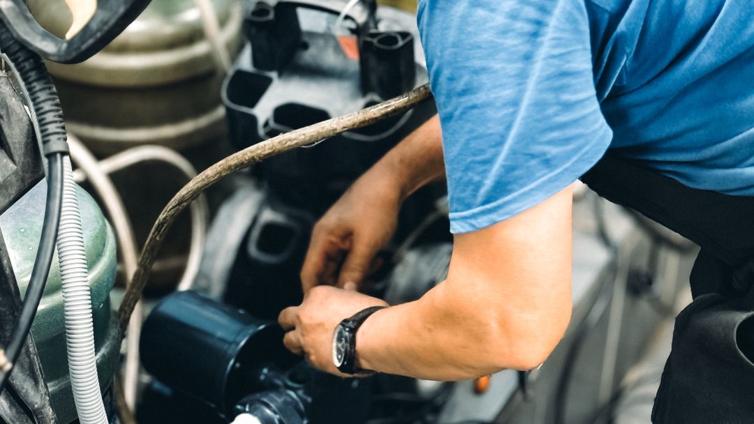 A mechanic working on a machine with hand tools