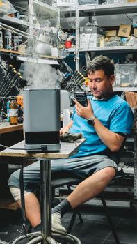 Young man in workshop using vintage equipment, surrounded by tools and smoke.