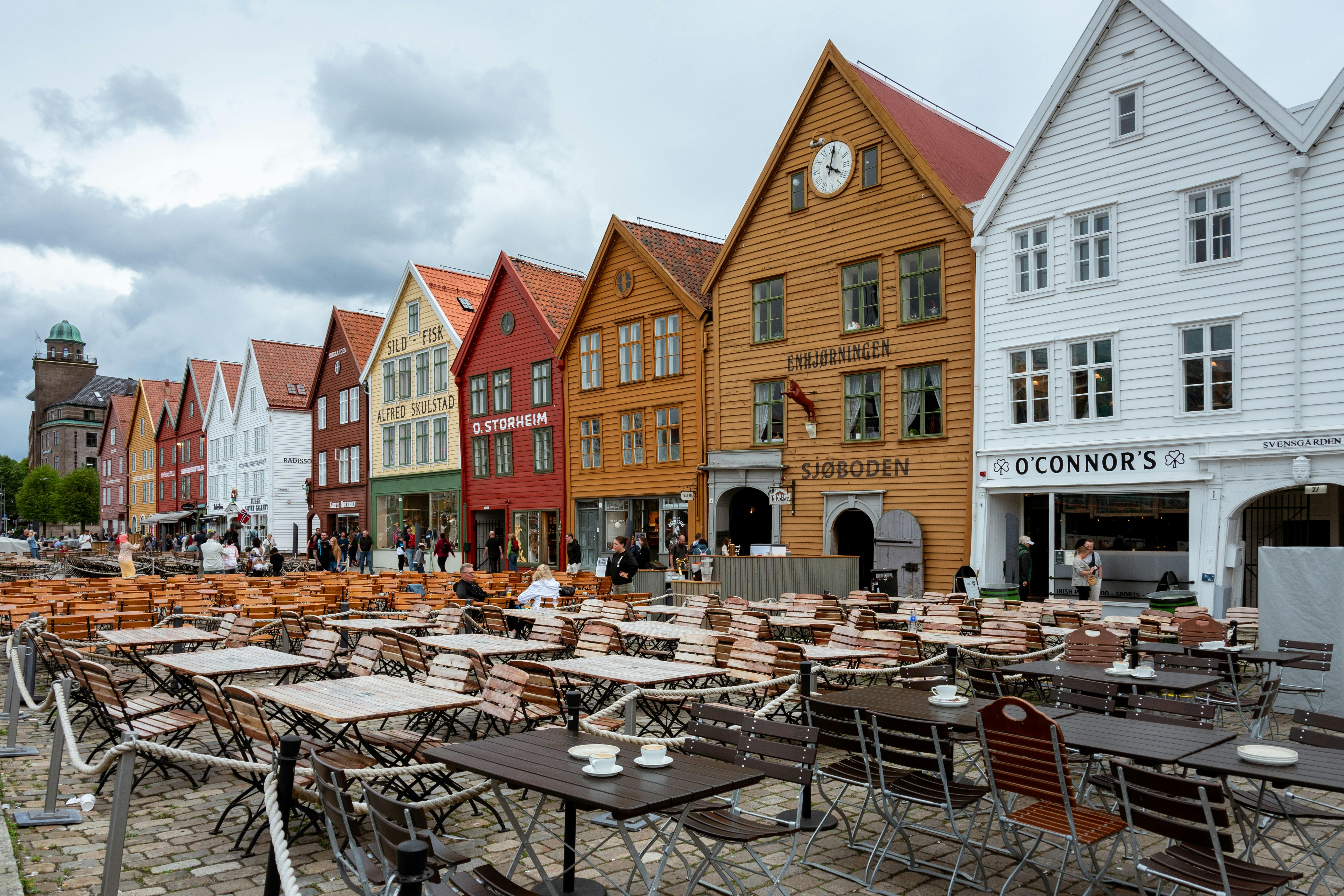 Colorful wooden buildings and outdoor cafes at Bryggen Wharf, Bergen, Norway.