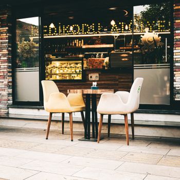 Charming outdoor cafe with stylish chairs and a vibrant interior. Perfect for urban lifestyle themes.