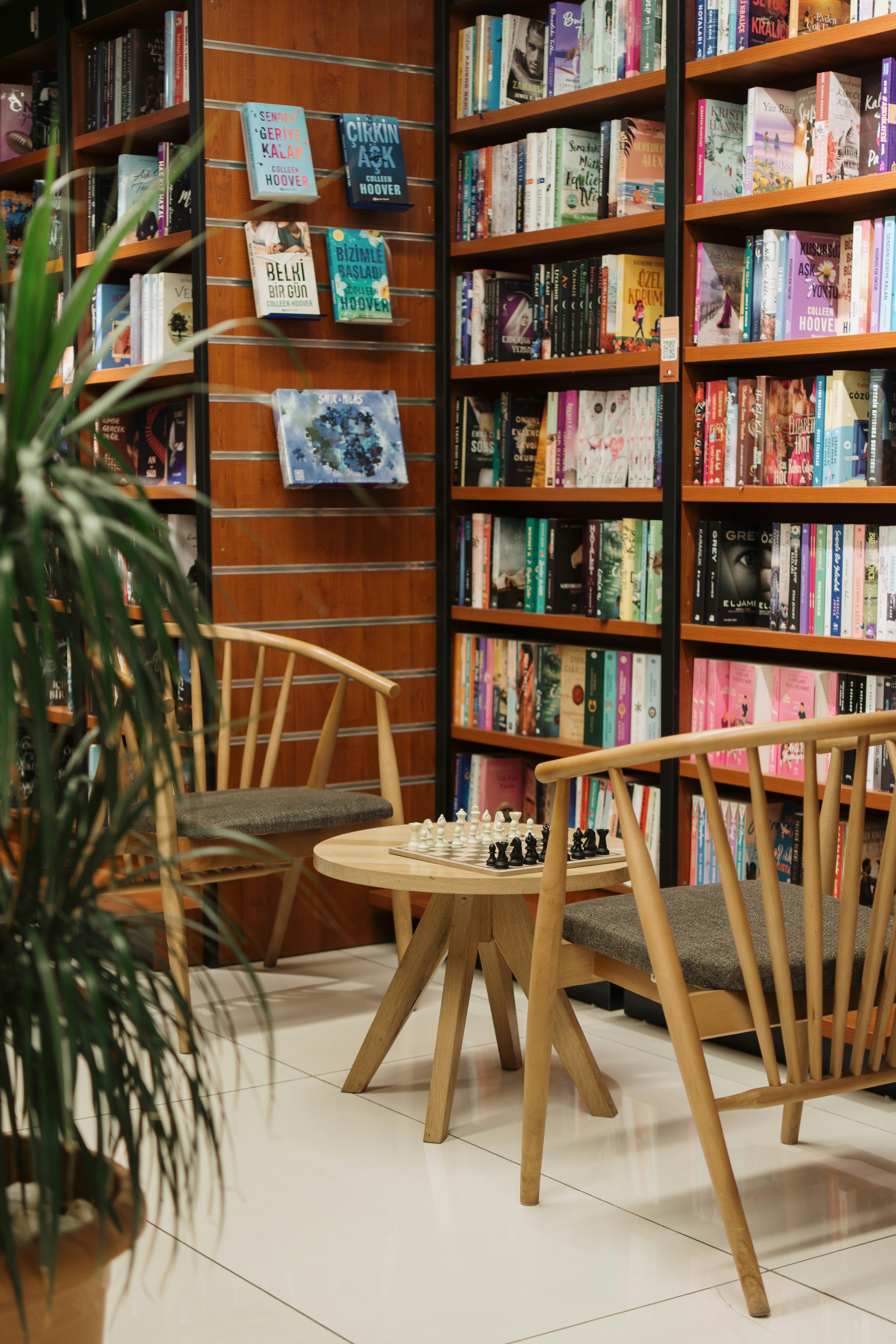 Gratuit Un colț fermecător de librărie, cu scaune din lemn, rafturi de cărți și un set de șah, care invită la relaxare atentă. Fotografie de stoc